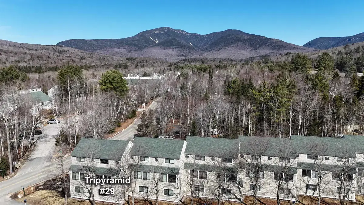 Rows of condominium townhouses in Waterville Valley in early spring with forested peaks rising behind